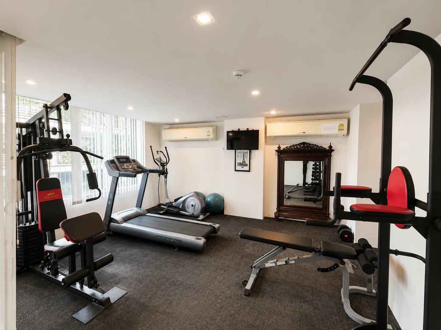 Condominium gym with treadmill, strength equipment, and exercise bench
